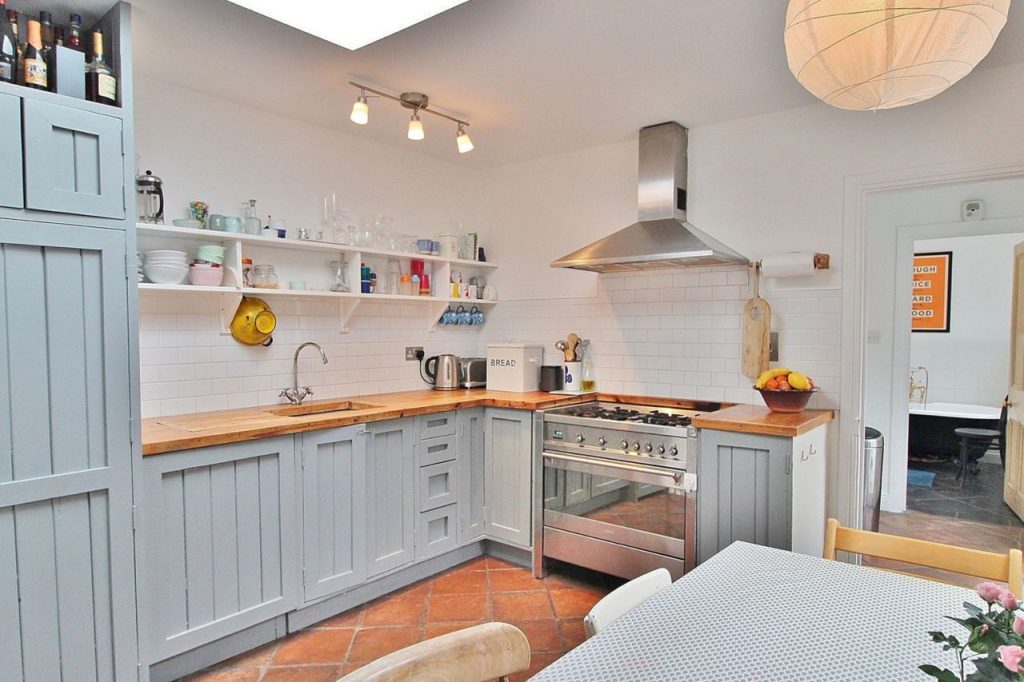 Image of a fully equipped light blue wooden kitchen with a stove, oven, and sink.