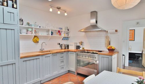 Image of a fully equipped light blue wooden kitchen with a stove, oven, and sink.